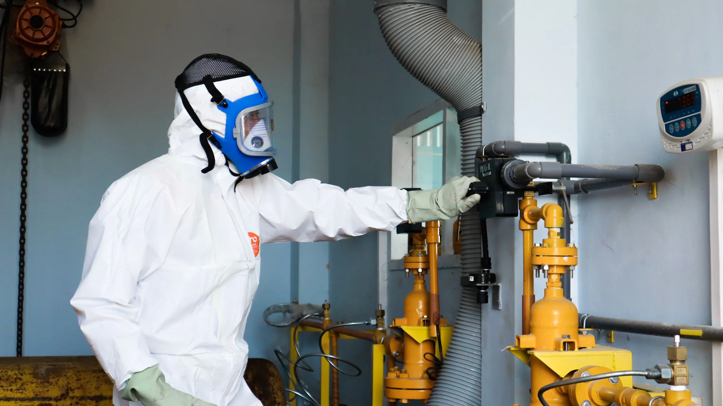 A worker in protective equipment inspecting an industrial process.